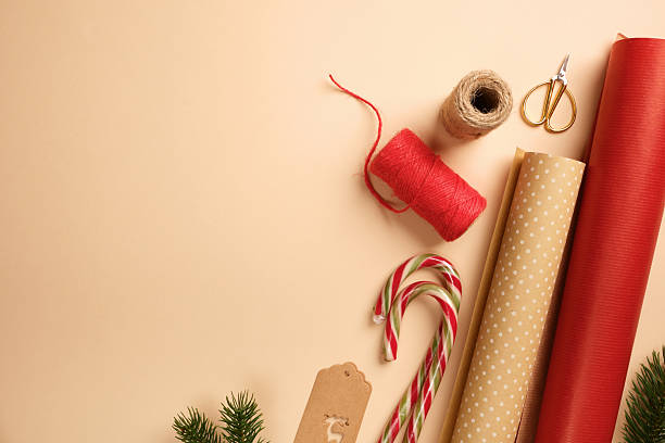 istock Christmas gift wrapping with red and brown wrapping paper, rope, labels, scissors, candy canes on beige backdrop. Copy space. 2248209144