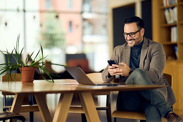 istock Affable Professional Man In Blazer Working On Smartphone At Modern Office Table With Laptop And Plant 2248209995