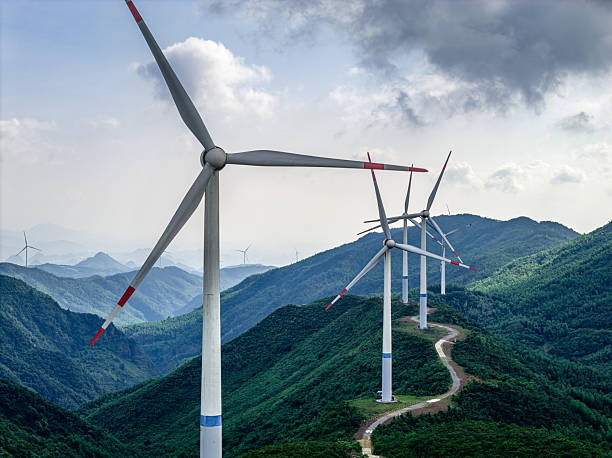 Giant wind generator producing renewable power on a mountain ridge with overcast skies.