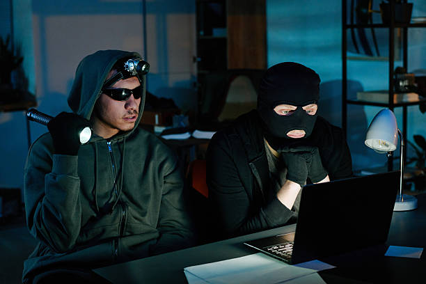 istock Two Young Adult Men Breaking into Office Computer during Nighttime Robbery 2248211558