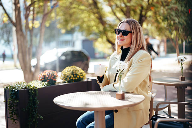istock Woman enjoying coffee outdoors on a sunny day in a relaxed cafe setting 2248211677
