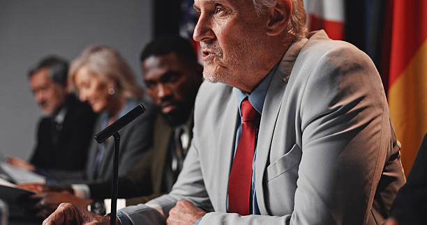 istock Press conference, speech and man with group for delegation, international government and panel. Summit, people and mature politician at seminar event for diplomacy discussion, global forum or policy 2248212330