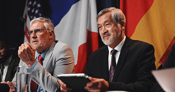 istock Press conference, tablet and men with group for delegation, international government and panel. Summit, mature people and politician at speech event for diplomacy discussion, global forum or policy 2248212344