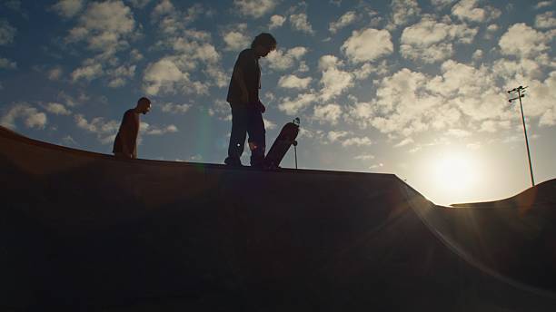 Skater standing on the ramp at skate park at sunset