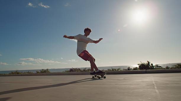 Young male surfer jumping for joy winning while gambling online using phone on beach.