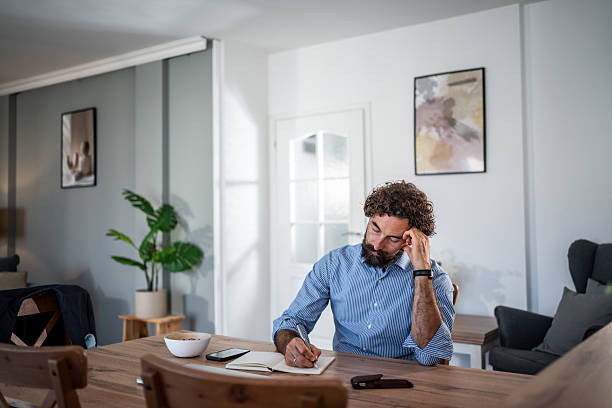 istock Man writing in a journal at home office during a relaxed morning 2248216495