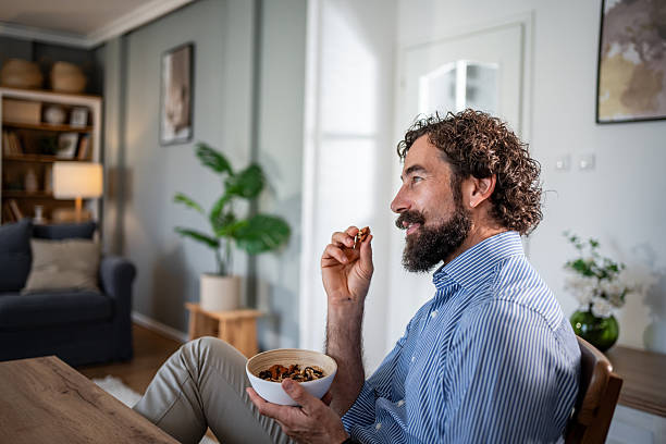 istock Man relaxing at home eating healthy nuts snack 2248216551