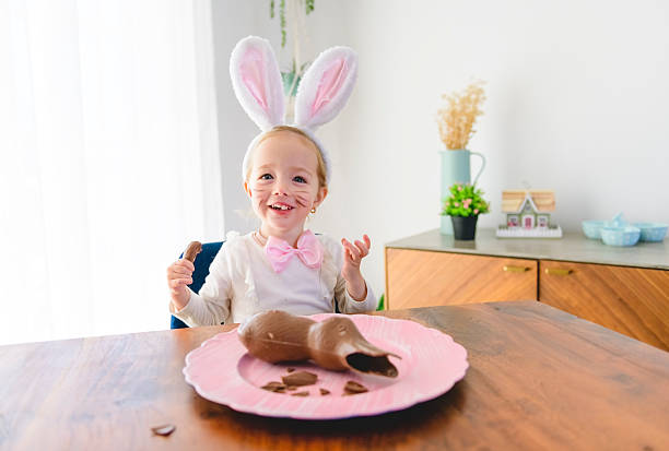 istock Little blond girl with dirty chocolate bunny ears eating Easter egg 2248216740