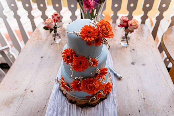 Three tier blue iced wedding cake with orange sugar flowers