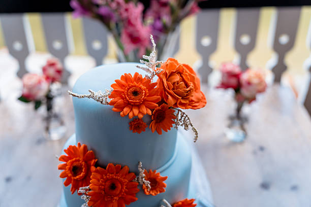 Three tier blue iced wedding cake with orange sugar flowers