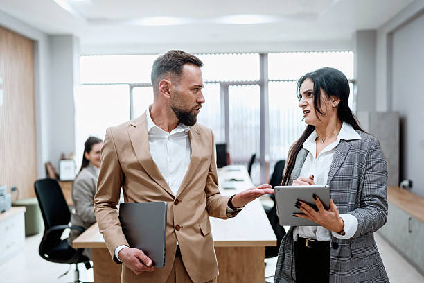 istock Two business colleagues discussing work in modern office environment 2248217256