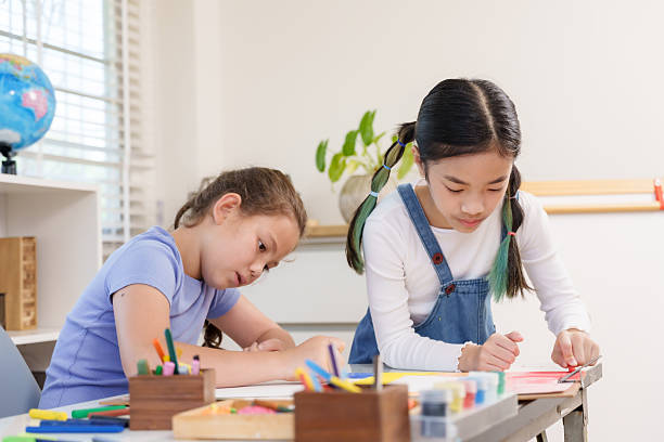 istock Asian girl and caucasian girl elementary students cooperating on classroom crayon project representing creativity imagination teamwork friendship childhood positive collaborative artistic learning 2248222487