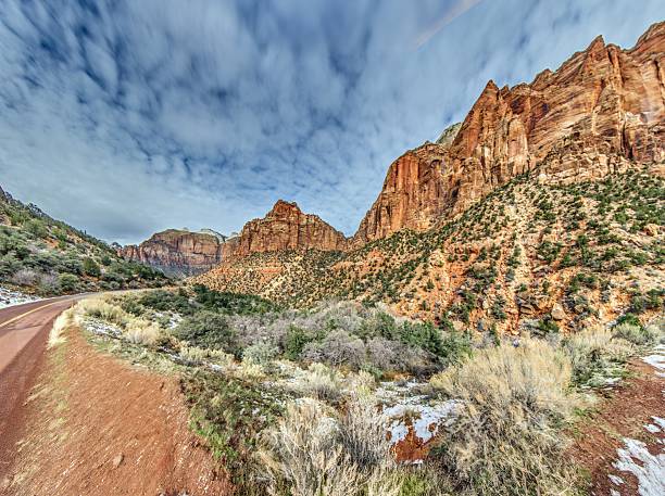 Winter canyon scene in Zion National Park with sandstone cliffs, river and snowy terrain.