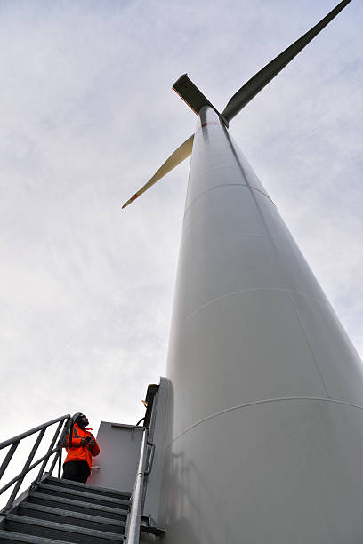 istock A technician stands under a huge wind turbine and looking up. 2248229307