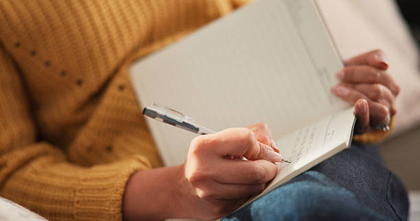 istock Woman, hands or writing on couch with journal for planning goals, creative idea or process emotions. Daily reflection, notes or person in home with diary for self improvement, inspiration or insight. 2248231759