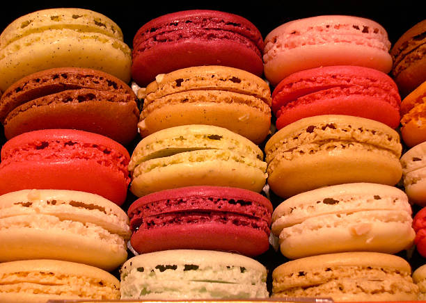 a variety of colorful macarons stacked on the shelves of a large pastry shop