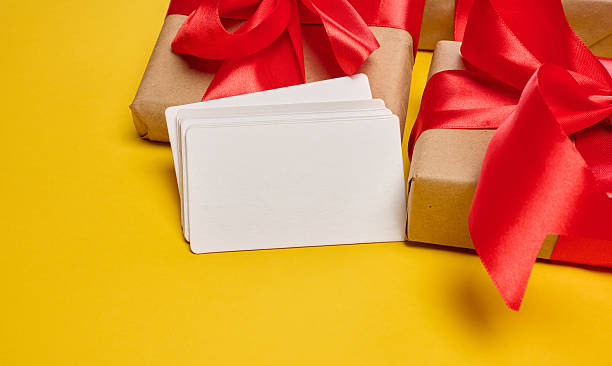 Blank white paper business card and gift boxes on yellow background