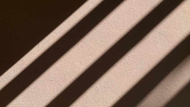 istock Abstract pattern of geometric striped shadows and natural sunlight falling dramatically on a textured white concrete wall background with empty copy space. 2248233867