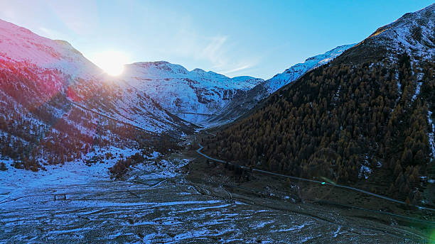 Sunrise over snowcapped mountains and forest in autumn with fresh snow, Livigno, Swiss Alps