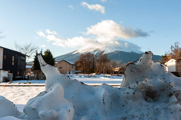 Fujikawaguchiko, Japan - December 26, 2019. Outdoor scene showing a residential area in the Japanese town of Kawaguchiko, with mount Fuji being prominent in the background. It is winter in this snowy landscape.