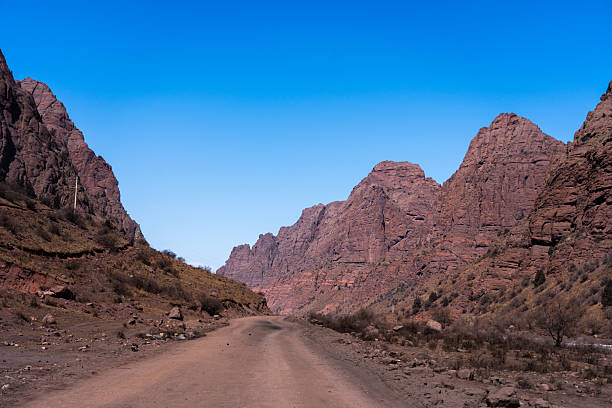 istock Unpaved road winding into a tight valley with rocky red cliffs 2248239045
