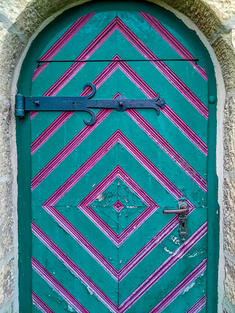 Old wooden church door with colourful paint in turquoise and magenta