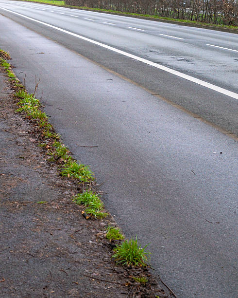 istock Empty asphalt road with grass growing on the sidewalk 2248246985