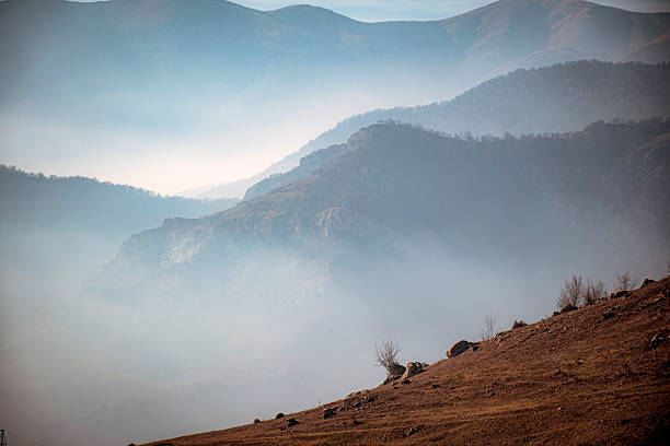 Mountain peak seen through the dense fog. Rainy scene in the mounts, hiking in the mist landscape