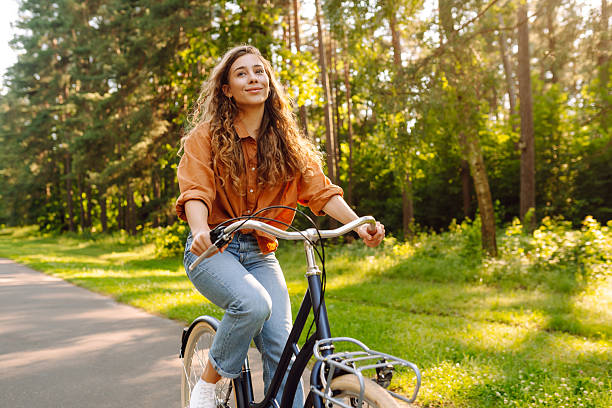 istock A cheerful woman rides a bicycle along a path in a vibrant green forest. 2248248757