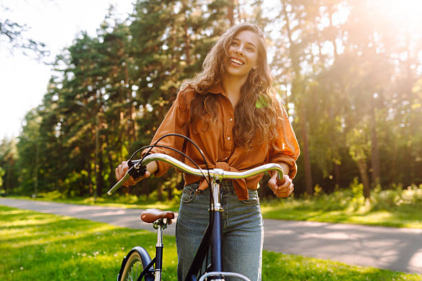 istock A cheerful woman rides a bicycle along a path in a vibrant green forest. 2248248761