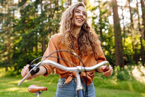 istock A cheerful woman rides a bicycle along a path in a vibrant green forest. 2248248814