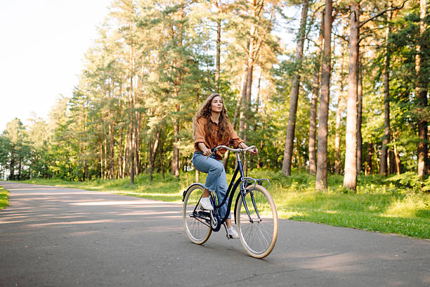 istock A cheerful woman rides a bicycle along a path in a vibrant green forest. 2248248863