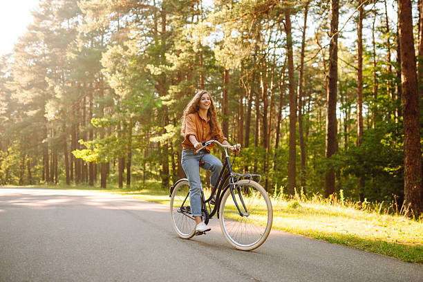 istock A cheerful woman rides a bicycle along a path in a vibrant green forest. 2248248873