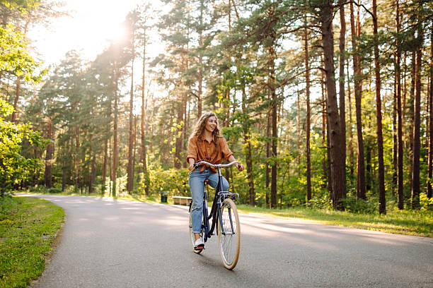 istock A cheerful woman rides a bicycle along a path in a vibrant green forest. 2248248890