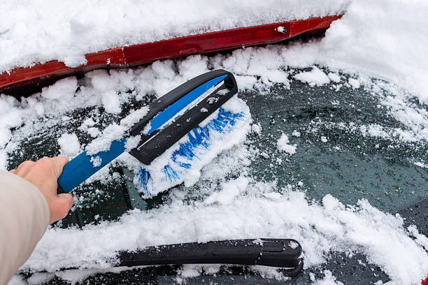 istock Clearing snow from a car window with brush 2248250173