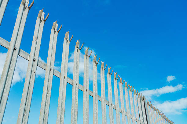 istock Security fence barrier extending against blue sky 2248250379