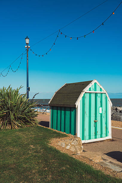 Unique green striped beach hut standing by the sea with a bright blue sky