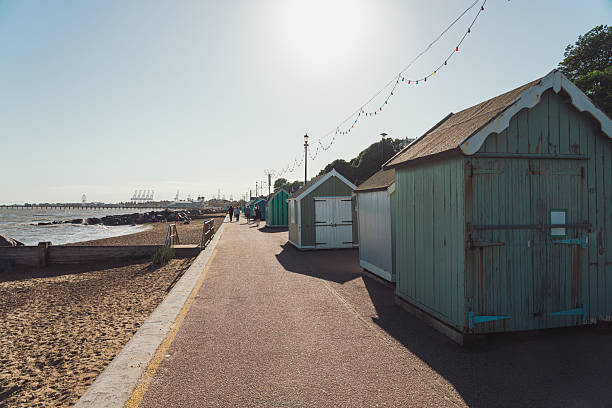 Beach huts lining the promenade on felixstowe beach with sun in sky