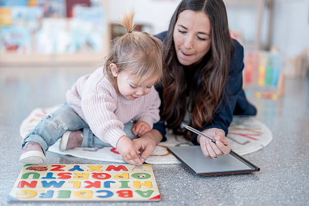 istock Mother And Daughter Learning Together On Floor With Alphabet Puzzle And Tablet 2248250521