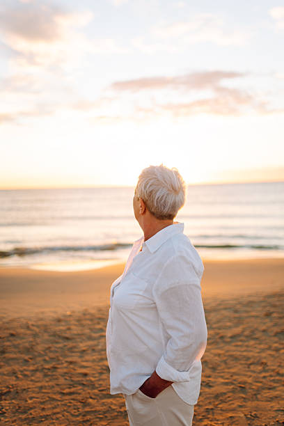 istock A joyful elderly woman feels free as she strolls along a sandy beach at sunset. 2248250555