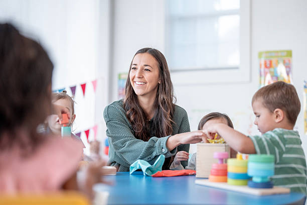 istock Friendly Female Teacher With Kids At Colorful Classroom Table Engaging In Hands-On Activity 2248253127