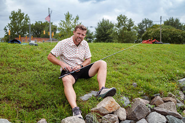 Man smiling while lying among forest leaves and mushrooms, evoking a playful and joyful mood, emphasizing connection with nature and creativity in an outdoor and whimsical context.