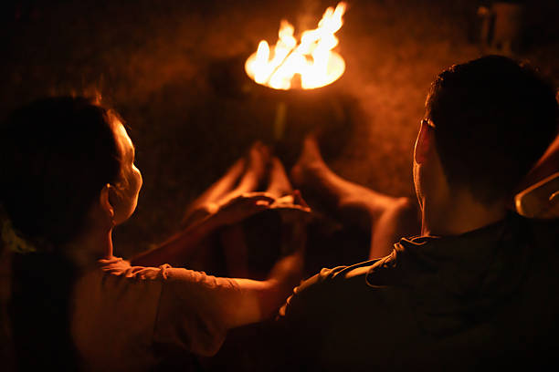 istock Couple sitting by warm campfire. 2248254583