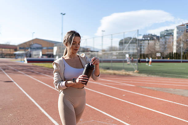 istock Young woman hydrating with protein shake on running track 2248256068