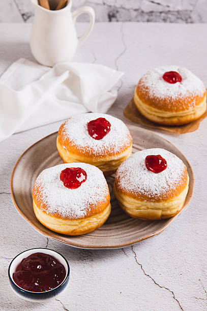 istock Delicious jam filled donuts with powdered sugar on a plate on the table vertical view 2248257361