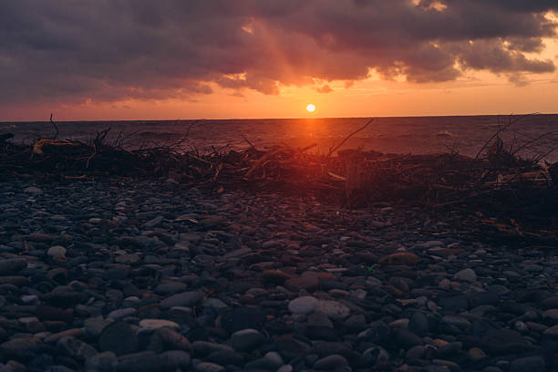 Sunset over the sea with red setting sun, Batumi pebble beach. High quality photo