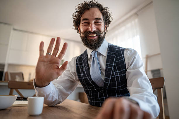 istock Stylish man waving hello during video call from home 2248259735