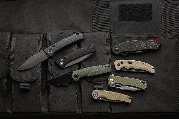 istock A collection of six modern folding knives displayed on a black tactical gear surface. 2248261948