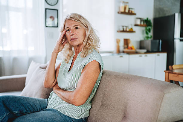 istock Pensive Senior Woman Sitting Alone on Sofa Looking Sad and Lonely 2248262850