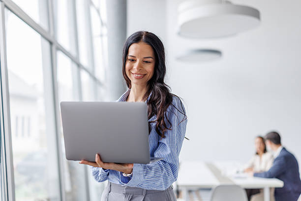 istock Businesswoman standing in modern office using laptop 2248265227